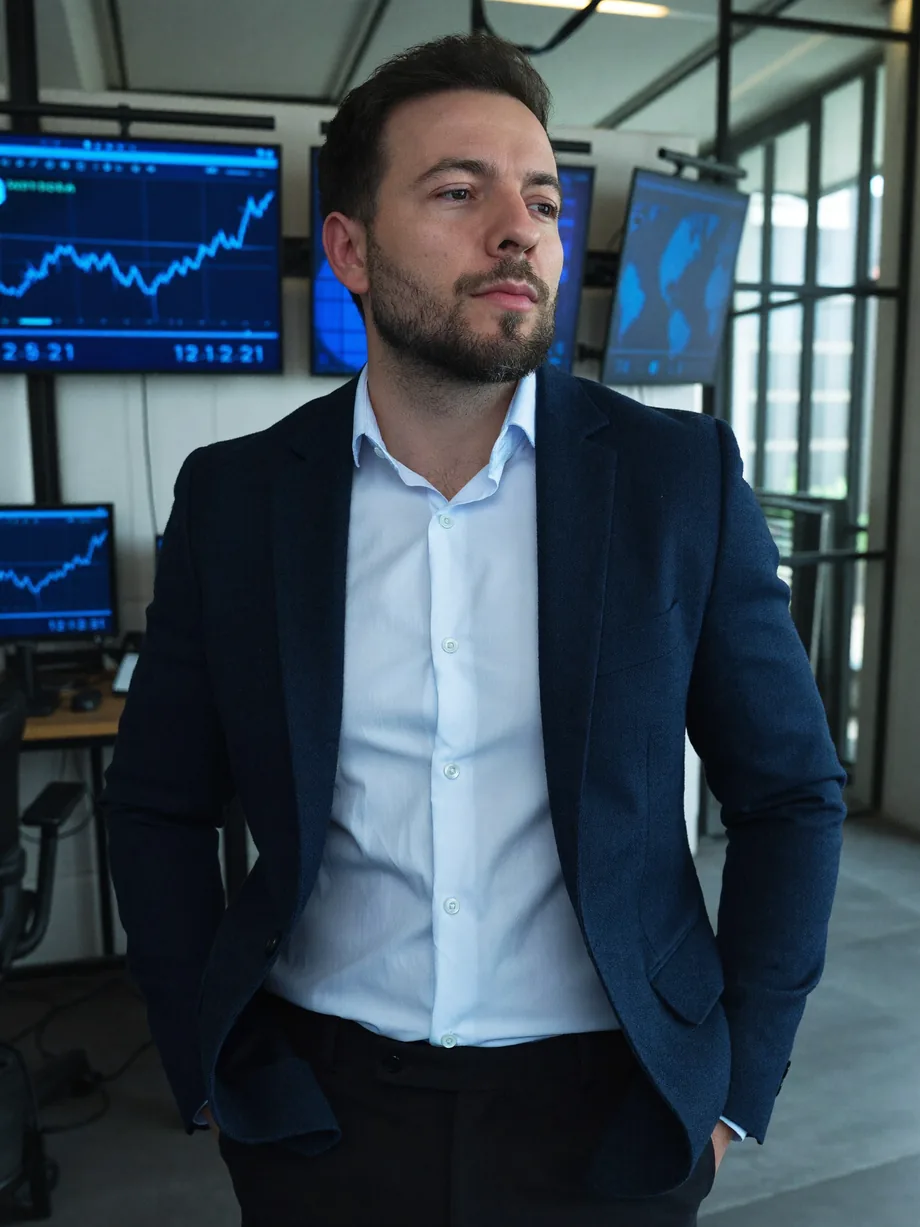 Elton Plácido em ambiente de mercado financeiro, com telas e gráficos ao fundo